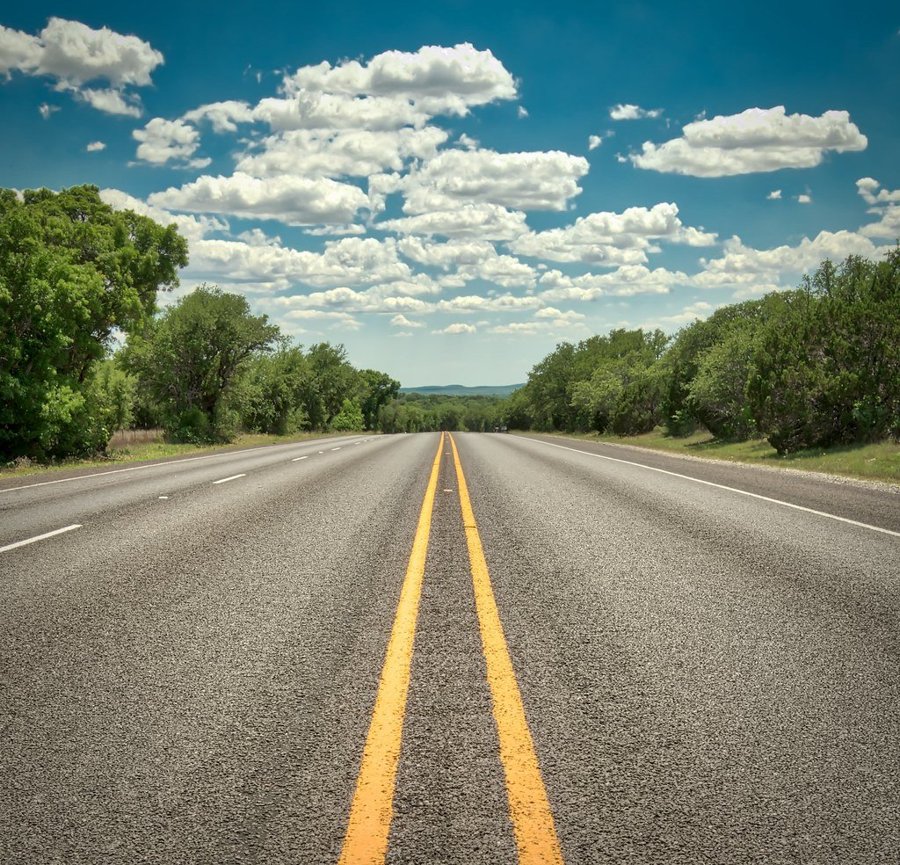 青空の下にまっすぐ伸びる2車線の道路の写真