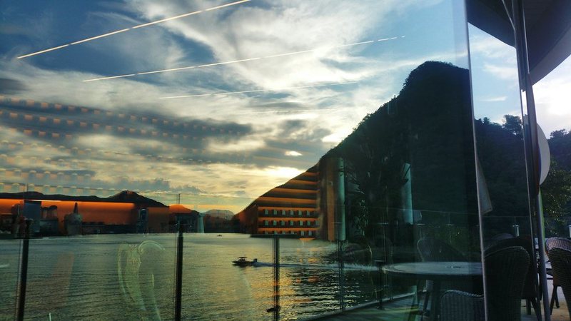 列車の窓ガラス越しに、夕暮れの湖と山の稜線が見える写真